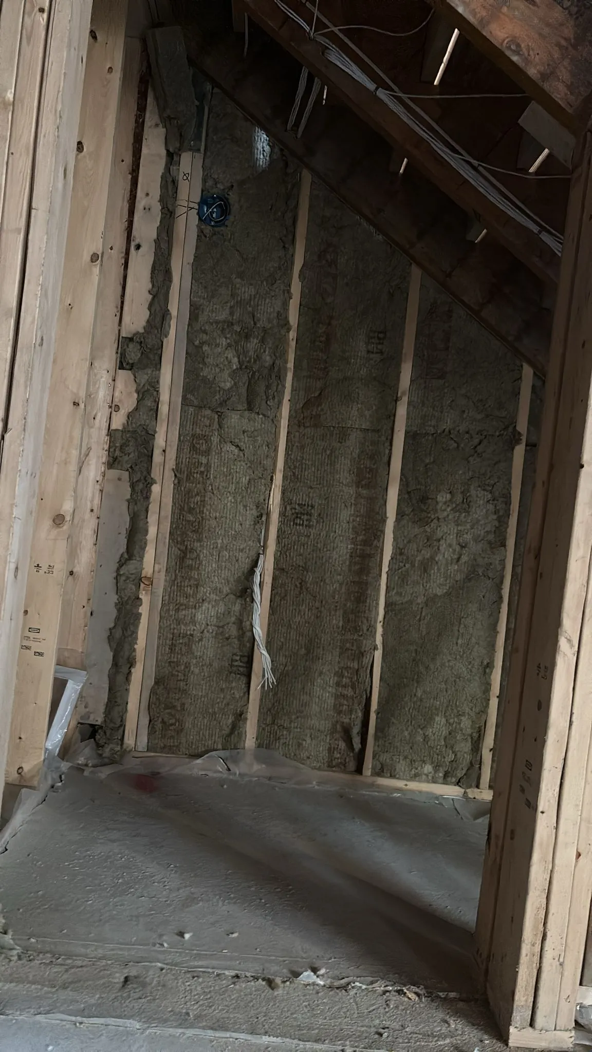 Fibre batt insulation fitted into a sloped attic knee-wall