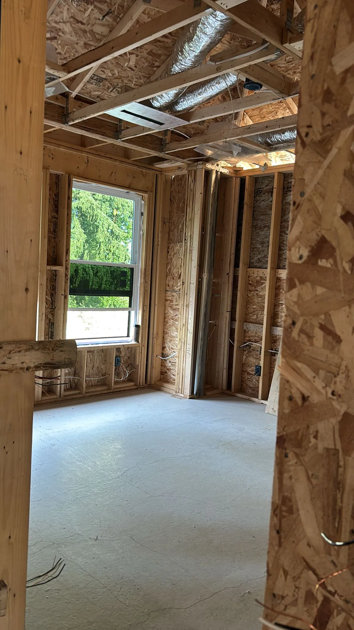 OSB-sheathed interior framing with a window and ceiling ductwork